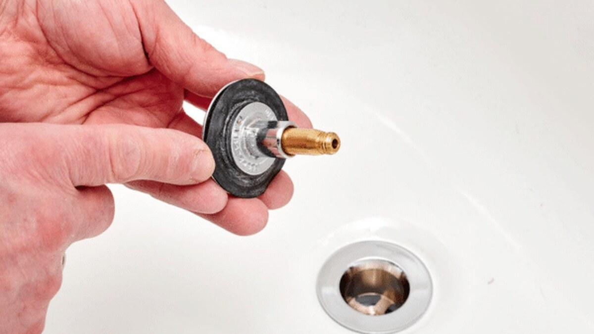 Tháo bộ nút thoát nước bồn tắm bị kẹt gồm đĩa chặn cao su và trục vít đồng khỏi bồn