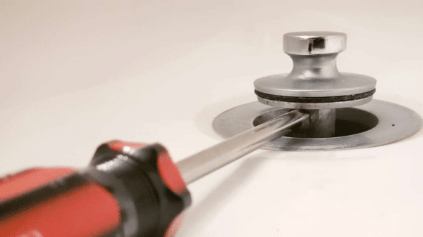 Tháo vít cố định nút nhấn bồn cầu bằng tua vít đầu dẹt